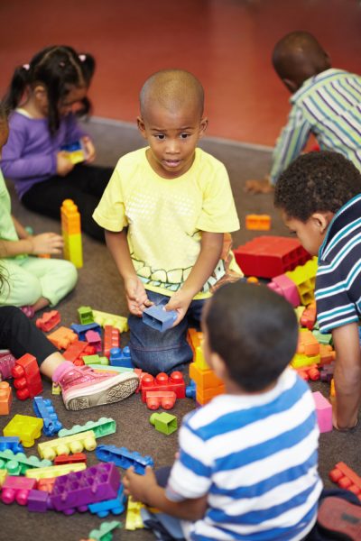 Sharing is caring. Play time for a group of young children who are playing with plastic blocks